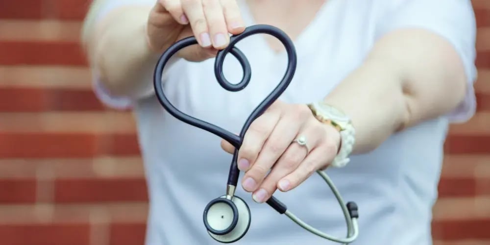 Healthcare worker holding a stethoscope in a heart shape, symbolising duty of care in aged care.