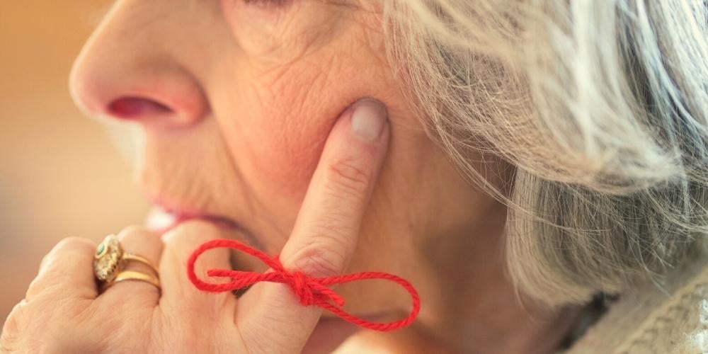 An elderly lady with dementia who has a reminder string tied to her finger.