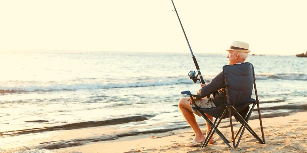 Elderly person with limited mobility fishing on a beach in Australia as a fun activity.