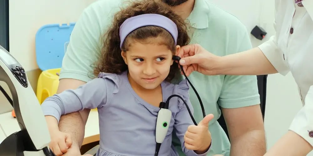 Young girl undergoing a hearing test, with a clinician using equipment to check for sensory hearing loss.
