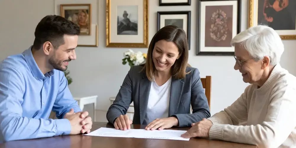 A family and a care professional smiling while reviewing documents to plan for senior in-home care and professional assessment.