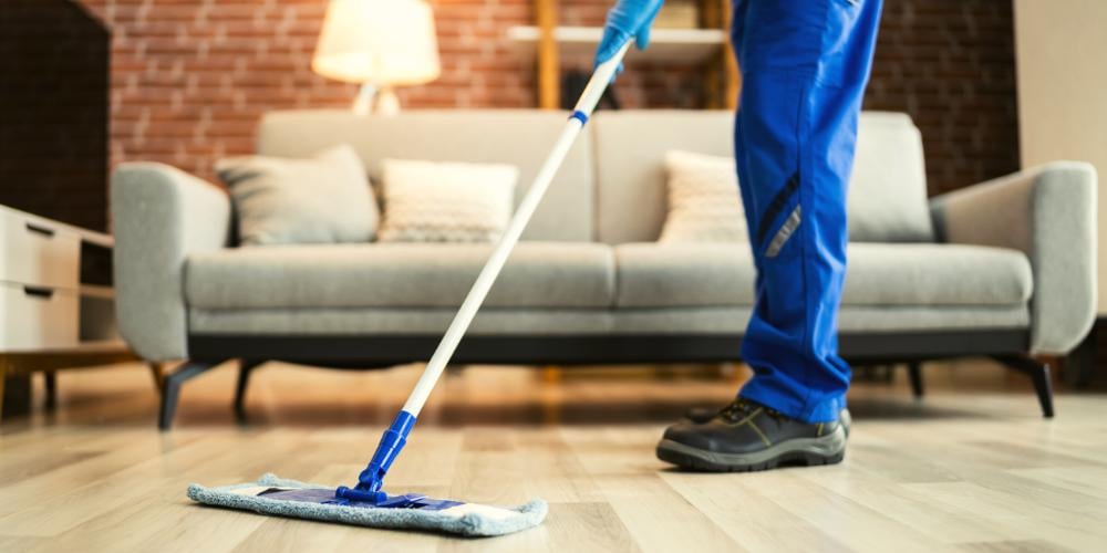 An NDIS cleaner mopping teh floor of his client's apartment.