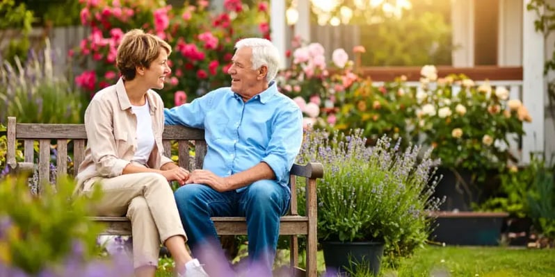 An older couple has a relaxed conversation on a garden bench, illustrating how to choose the right moment to discuss future in-home care and independence.