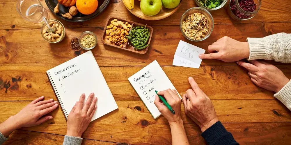 Overhead view of a family at a wooden table creating a checklist of questions to ask a potential in-home care provider, feeling organized and prepared.