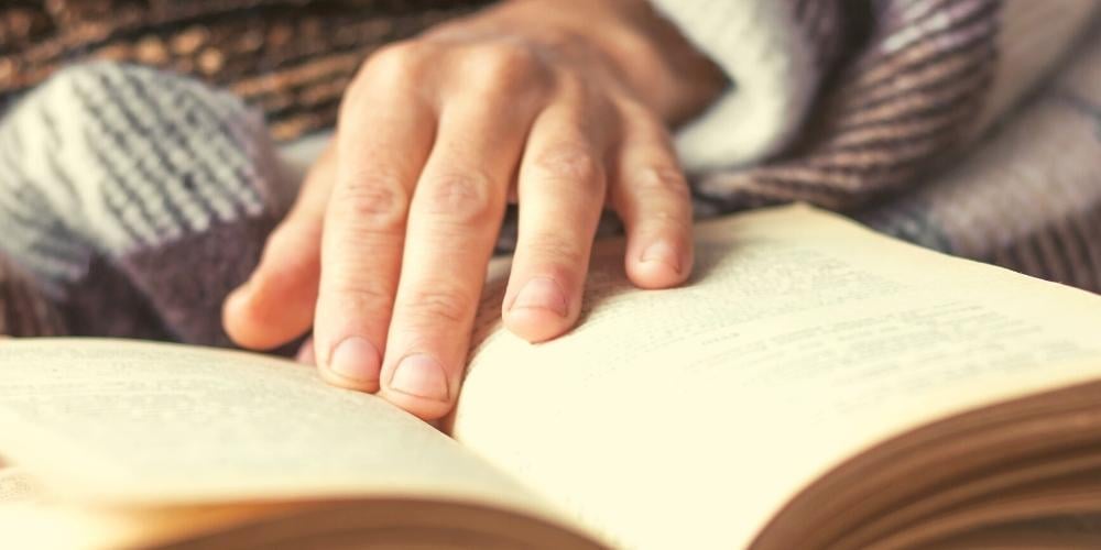 A photo of a dementia patient enjoying reading a book from the local library.