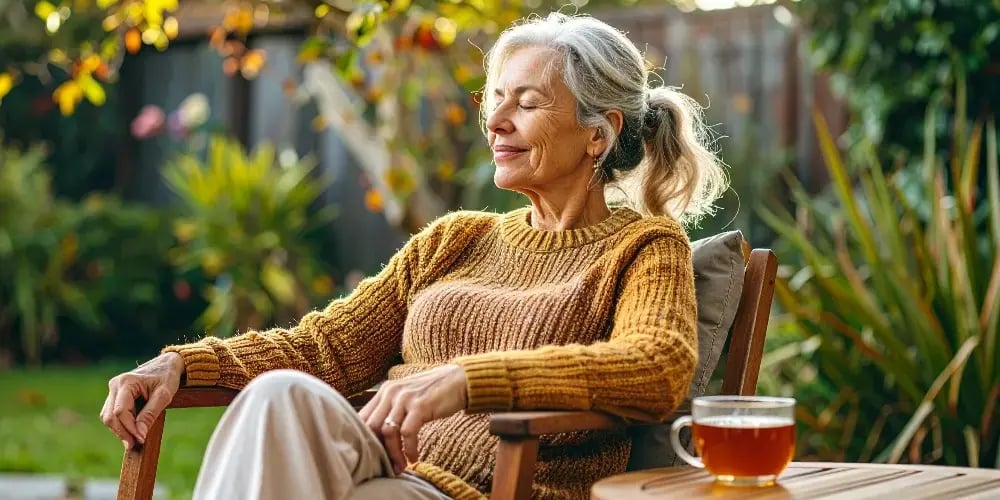A family caregiver takes a relaxing break in her garden with a cup of tea, highlighting the importance of respite care for maintaining wellbeing.