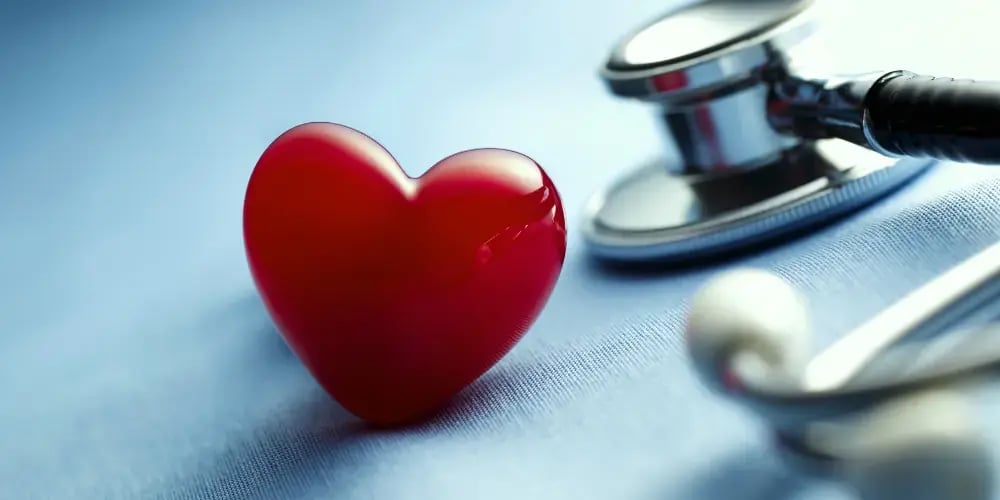 Close-up of a red heart and a stethoscope on a blue background, symbolising the health and well-being focus in respite care services.